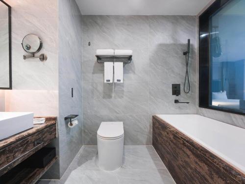 汉中丽柏酒店汉中中心广场高铁站的带浴缸、卫生间和盥洗盆的浴室