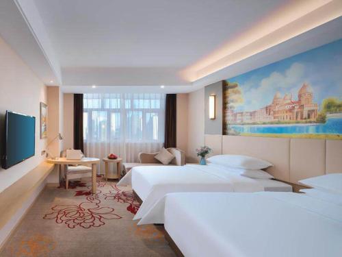 莆田维也纳国际福建莆田明珠酒店的一间卧室设有两张床,墙上挂着一幅画