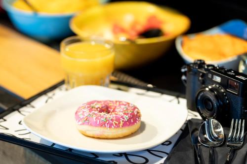 卡萨诺韦米兰马尔彭萨机场慕奇夕酒店的一张桌子上带相机的盘子上的甜甜圈