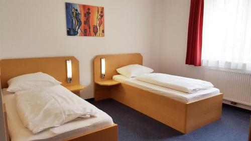 贡特拉姆斯多夫G&K酒店的配有两盏灯的小房间内的两张床