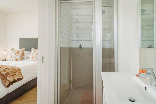 乔治304 Le Jardin的一间带玻璃淋浴的浴室和一张床