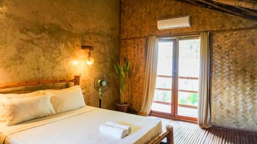 爱妮岛Happiness Vacation Villa El Nido的一间卧室设有一张床和一个大窗户