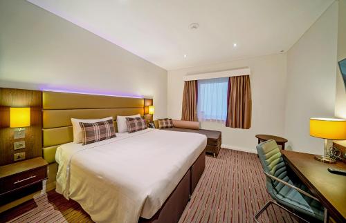 迪拜Premier Inn Dubai Al Jaddaf的酒店客房设有一张大床和一张书桌。