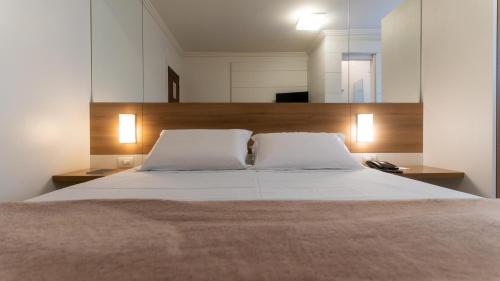布卢梅瑙Hotel Glória Blumenau的一间卧室配有一张带两个白色枕头的大床