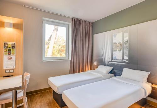 朗贡B&B HOTEL Bordeaux Langon的配有2张床的带桌子和2扇窗户的客房