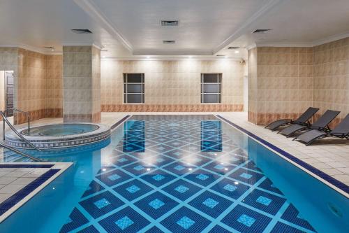 米德尔斯伯勒Leonardo Hotel Middlesbrough的游泳池设有蓝色瓷砖地板和浴缸