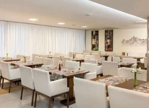 马卡埃Macaé Ramada Flat RJ的用餐室配有木桌和白色椅子
