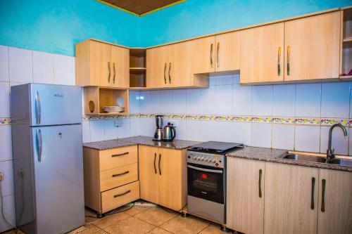 基加利RIGTH Homes的厨房配有木制橱柜和白色冰箱。