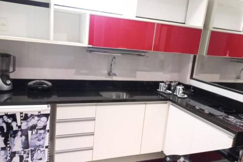 贝伦Loft em Belém的厨房配有红色和白色的橱柜和水槽