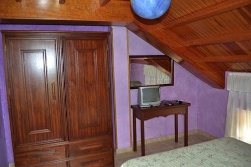 CoañaApartamentos Rurales Casa Ron的一间卧室配有一张床和一张书桌及电视