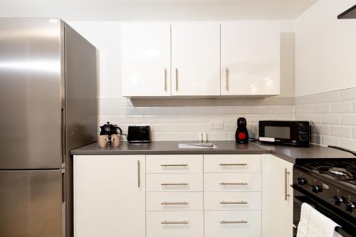 奥尔德姆Suite 5 - Stylist Spot in Oldham City Centre的厨房配有白色橱柜和不锈钢冰箱
