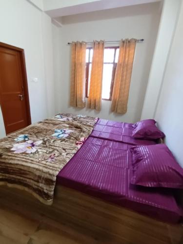 西姆拉Him Aaranya Home stay Shimla的紫色床单和窗户的客房内的一张床位