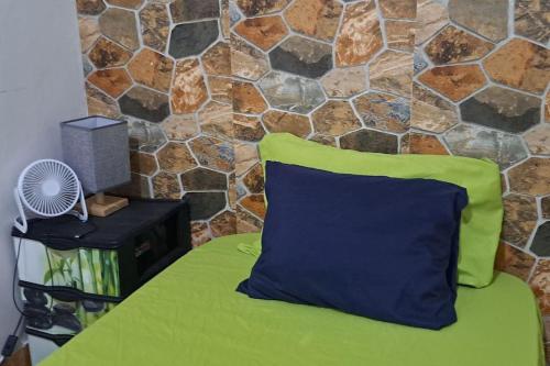 普拉亚In The Heart Of Praia - Family B&B的床上的绿色和蓝色枕头,带有石墙