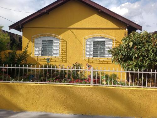 隆德里纳Simples e confortável的前面有栅栏的黄色房子