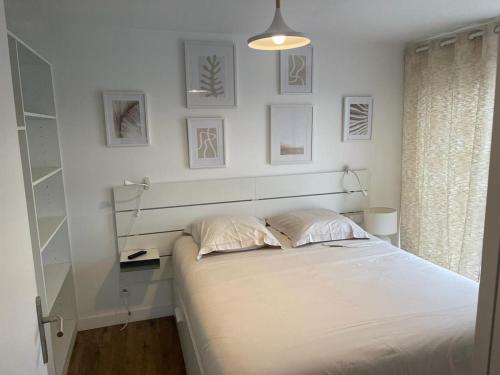 拉尔莫普拉格Cosy's Terrasse的白色卧室配有一张床,墙上挂有图片
