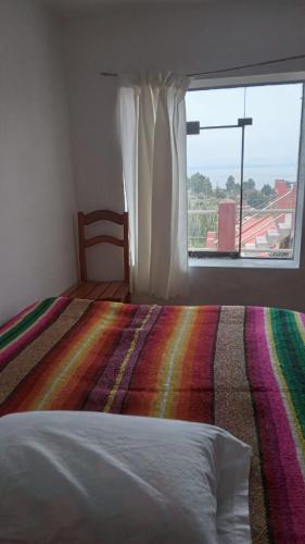 奥科苏尤Wiñay Wasi Occosuyo的一间卧室配有一张带彩色毯子和窗户的床。