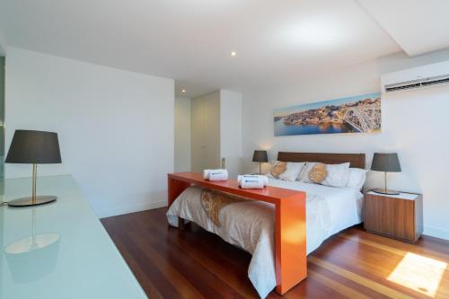波尔图Sunny Elegant Flat w/ Balcony - City Center的一间卧室配有一张床和一张带两盏灯的书桌。