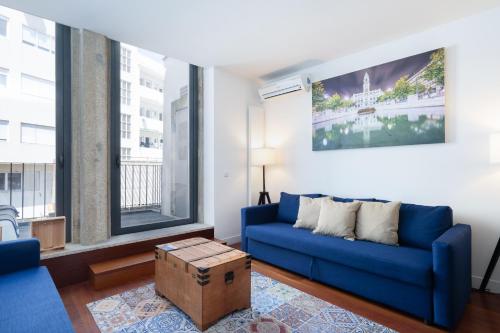 波尔图Sunny Elegant Flat w/ Balcony - City Center的客厅设有蓝色的沙发和2扇窗户。