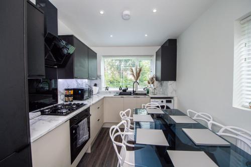 曼彻斯特Modern 4-Bed Retreat with Garden的厨房配有黑色橱柜和桌椅