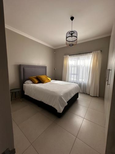 鲸湾港Cozy Home Self-Catering的一间卧室配有一张带黄色枕头的床和一扇窗户