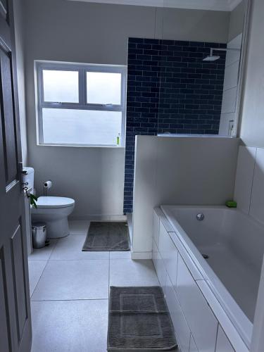 鲸湾港Cozy Home Self-Catering的带浴缸、卫生间和窗户的浴室