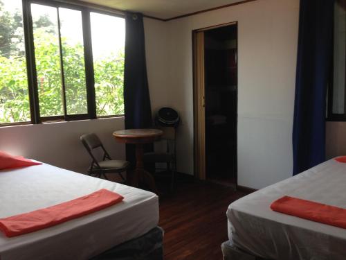Santiago EsteEL-CACIQUE-guesthouse-since-2003的客房设有两张床、一张桌子和窗户。