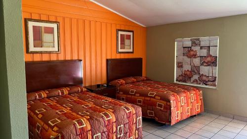 格林维尔格林维尔经济汽车旅馆的橙色墙壁的酒店客房内的两张床