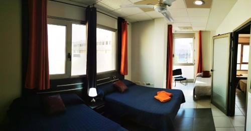 罗萨里奥港海滩附近2V豪华公寓 的一间卧室设有蓝色的床和2个窗户。