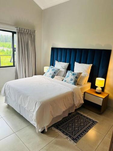 LobambaEkhaya Luxury Apartment的一间卧室配有一张大床和蓝色床头板