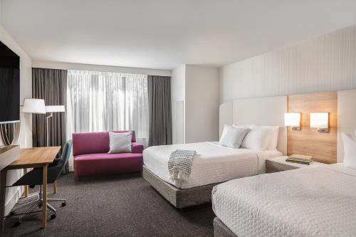 亚特兰大Crowne Plaza Atlanta Perimeter at Ravinia, an IHG Hotel的酒店客房,设有两张床和一张粉红色的椅子