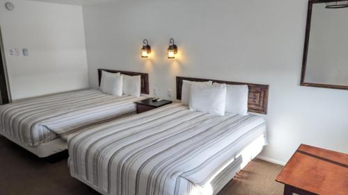 萨利纳High Desert Inn的配有白色墙壁的酒店客房内的两张床