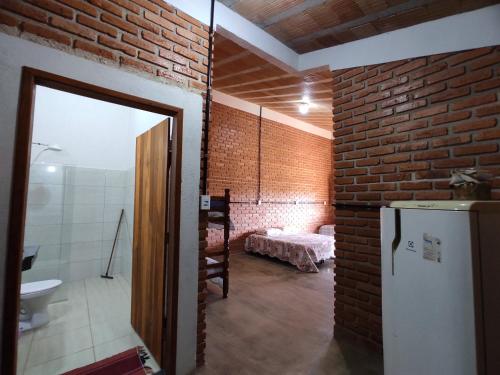 圣罗克迪米纳斯Pousada do Chicó的一间设有砖墙和冰箱的客房
