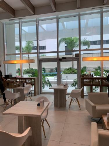 库里提巴Estúdio perfeito的餐厅设有桌椅和大窗户。