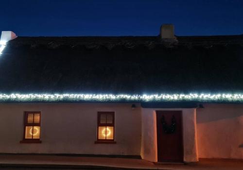 RushLuxury 300yr old Irish thatch cottage close to sea的夜晚屋顶上灯火的白色房子