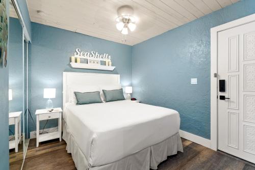 马拉松Seashells Getaway的卧室配有白色的床和蓝色的墙壁