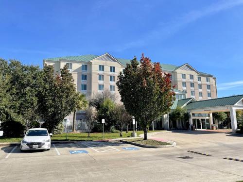 休斯顿ACP Hotel Westchase的停在大楼前停车场的汽车