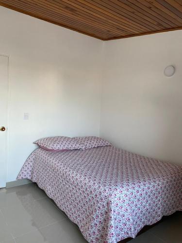 伊瓦格Paraíso House的一间卧室配有一张带粉红色床罩的床