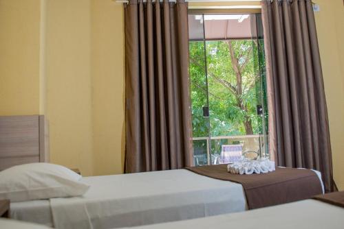 伊瓜苏Hotel Iguaçu Centro的一间卧室设有两张床和大窗户