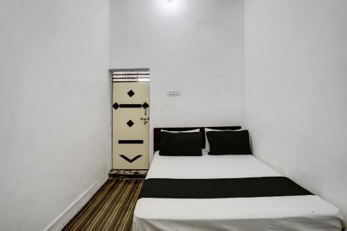 JhājharSuper OYO New River View的小卧室配有带白色床单和黑色枕头的床