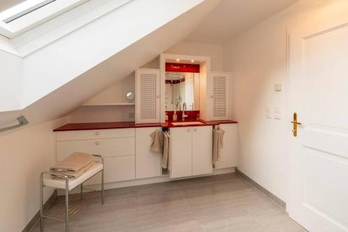 AdnetLuxus Alpenparadies nahe Salzburg Sauna & Whirlpool的阁楼厨房配有白色橱柜和楼梯