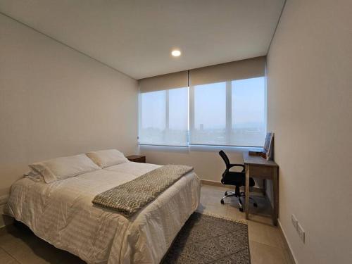 墨西哥城Cómodo Departamento的一间卧室配有一张床、一张书桌和一个窗户。