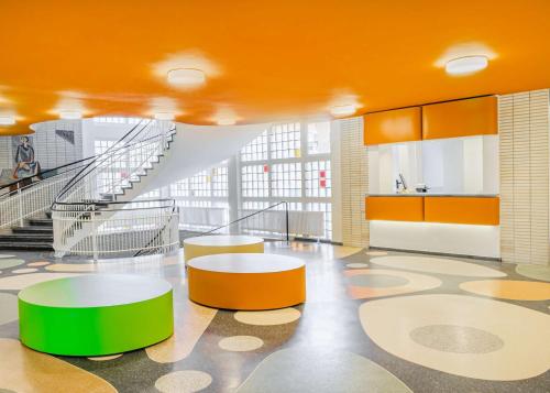 多特蒙德prizeotel Dortmund-City的大堂设有橙色和绿色的桌子和楼梯