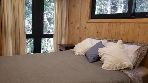 巴拉斯港Cabaña Bosque Rio的一间卧室配有带3个枕头的床