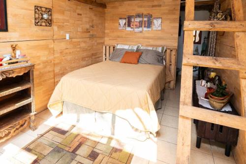 Santa Cruz VerapazCabaña Colibrí的卧室配有一张床铺,位于带木墙的房间内
