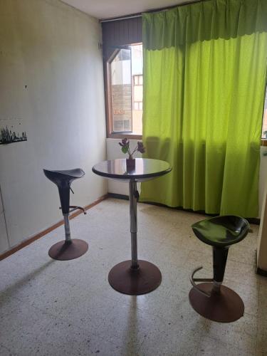 伊洛Sientete en casa的绿窗帘的房间的两把凳子和一张桌子