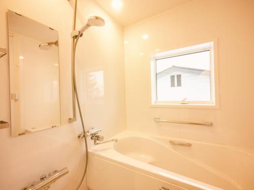白马村古民家ホテル 結 YUWAI的白色的浴室设有浴缸和窗户。