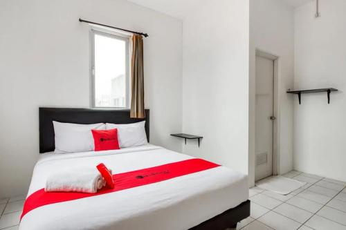 WatulawangRedDoorz Plus near Galaxy Mall的卧室配有带红色枕头的大型白色床