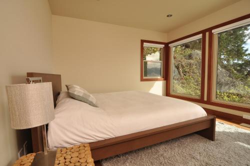 Madeira ParkExclusive Private Island - Pacific Ocean Paradise的一间卧室设有一张床和两个窗户。