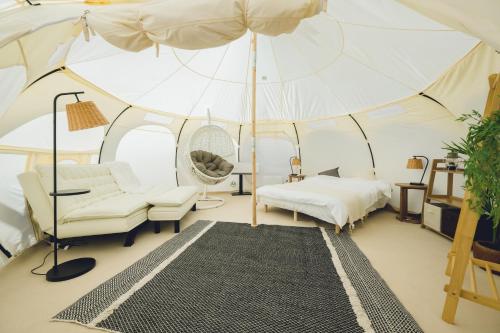 名户Yagaji Beach(屋我地ビーチ)的一个带帐篷的房间,配有一张床和一把遮阳伞