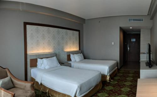 沙马林达Five Premiere Hotel的酒店客房,配有两张床和椅子